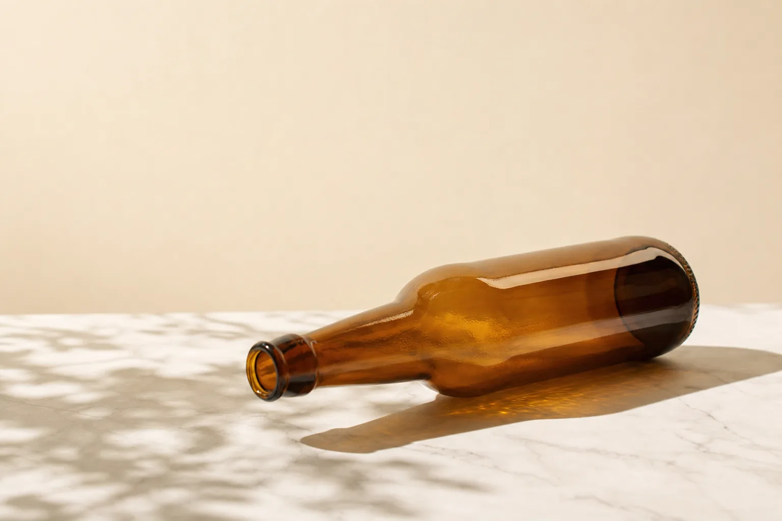 Garrafa de cerveja âmbar em close sobre mármore branco